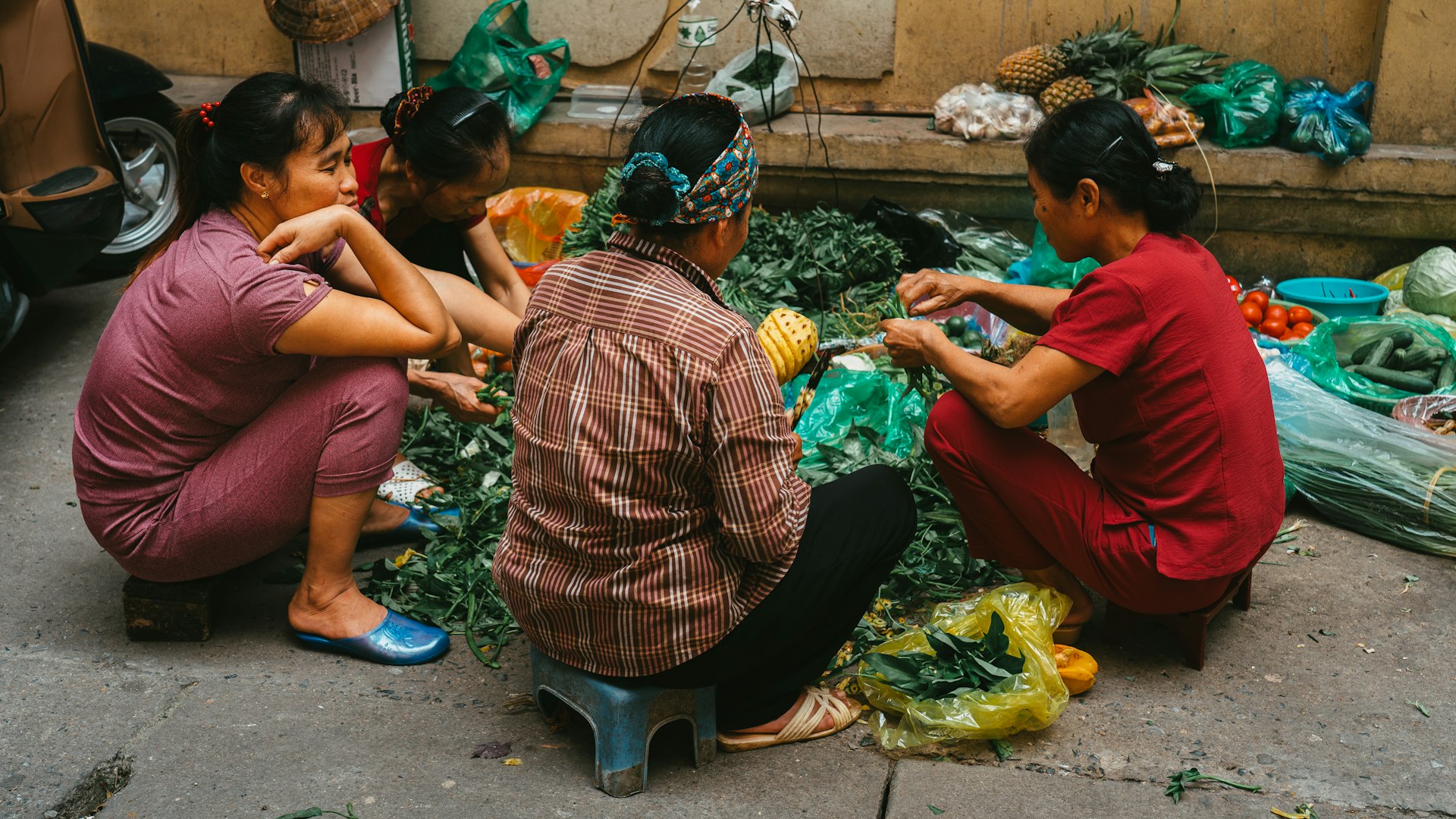 Women are gathered around a pile of fresh greens.